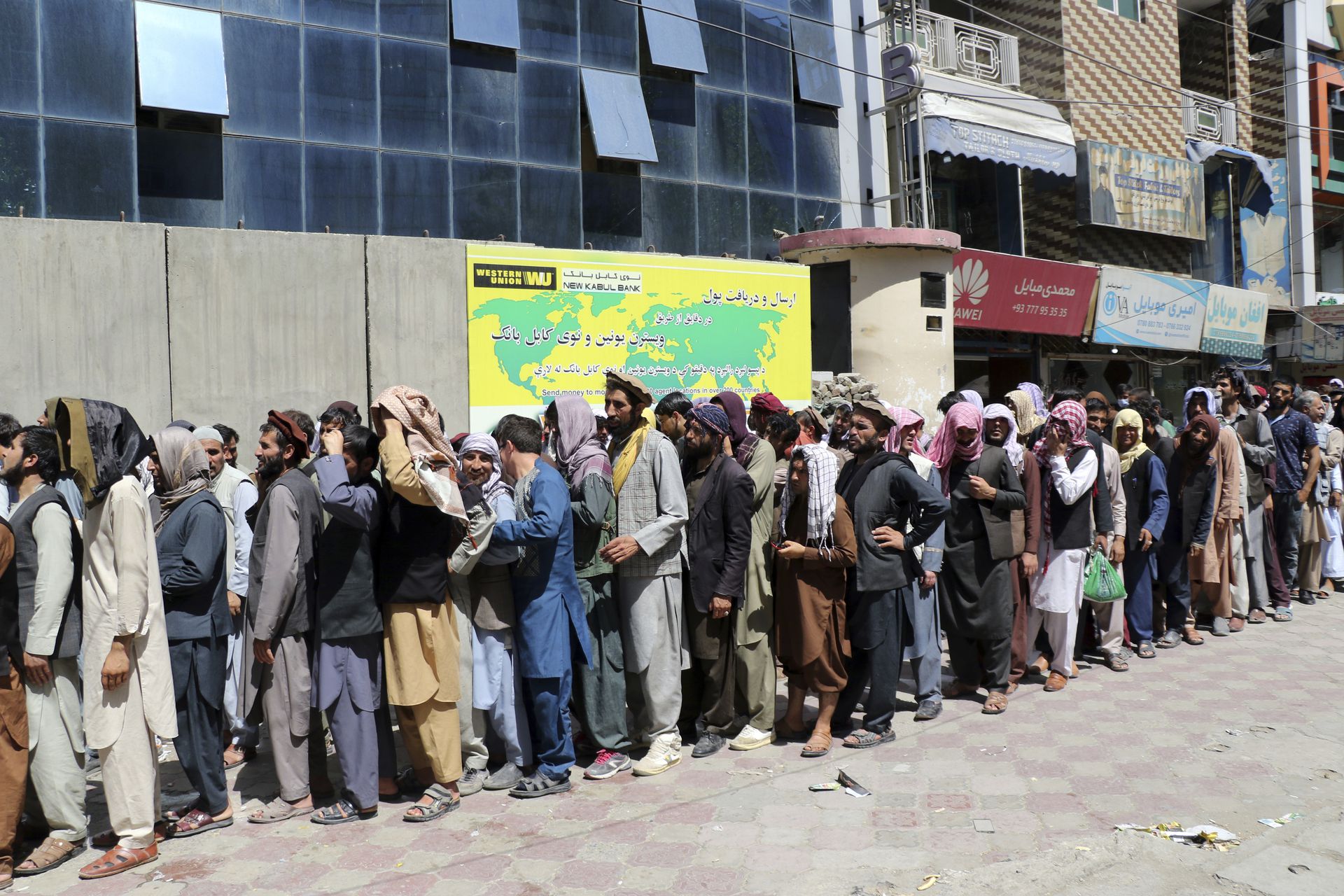 Afganos esperan fuera del Kabul Bank en Kabul.  Los talibanes recuperaron el control de Afganistán casi 20 años después de que fueron derrocados en una invasión liderada por Estados Unidos tras los ataques del 11 de septiembre.  Su regreso al poder ha empujado a muchos afganos a huir por temor a represalias de los combatientes o un regreso al brutal gobierno que impusieron la última vez que gobernaron el país.